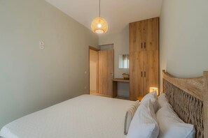 A bedroom with a bed, wooden wardrobe, and a hanging light fixture. - Aria Guest Residence, Apartment (Galatas)