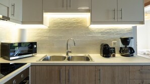 A modern kitchen with a microwave, double sink, coffee maker, and a toaster.