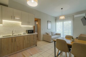 A modern kitchen with a built-in microwave, wooden cabinets, and a large window providing natural light. - Aria Guest Residence, Apartment (Galatas)