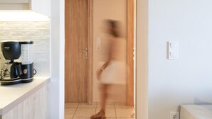 A kitchen area with a coffee maker and a wooden door.
