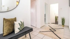 Ein moderner Flur mit einem runden Spiegel, einer Bank mit Kissen und einem geometrischen Teppich.