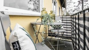 Ein Balkon mit Tisch, Stühlen, einer Topfpflanze und dekorativen Vasen.