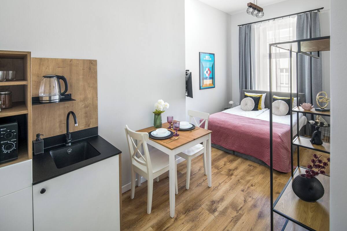 Una habitación funcional con kitchenette, comedor y cama.