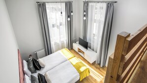A modern bedroom with two beds, a TV, and a wooden bench. - Horizon Park Aparthotel (Kraków)