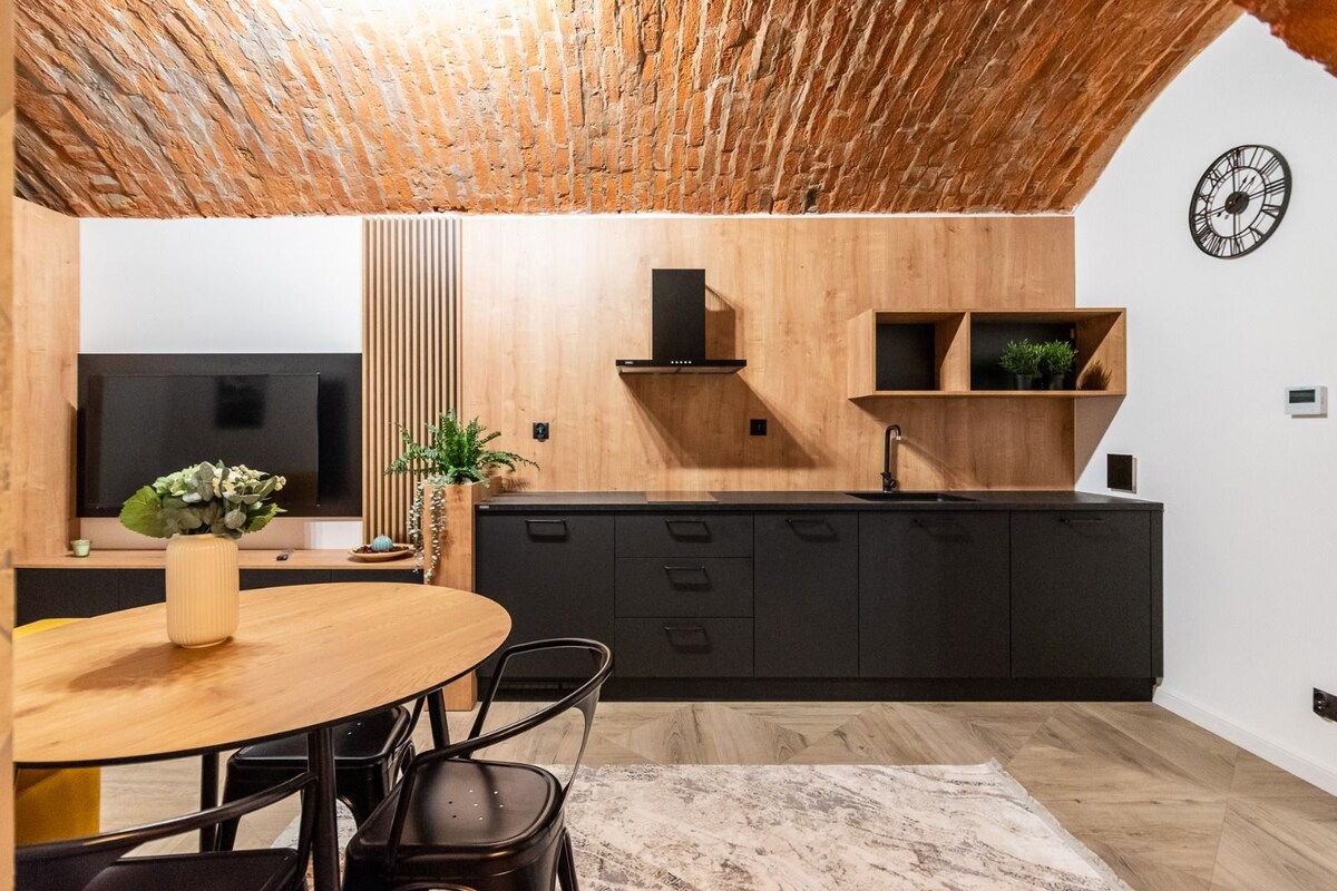 A modern kitchen with wooden cabinetry, a built-in stove, and a black countertop.