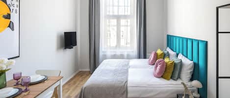 A modern bedroom with a bed, bedside table, and a window with curtains.