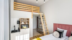 A compact bedroom with a bunk bed, a kitchenette, and a ladder leading to an upper bunk. - Horizon Park Aparthotel (Kraków)