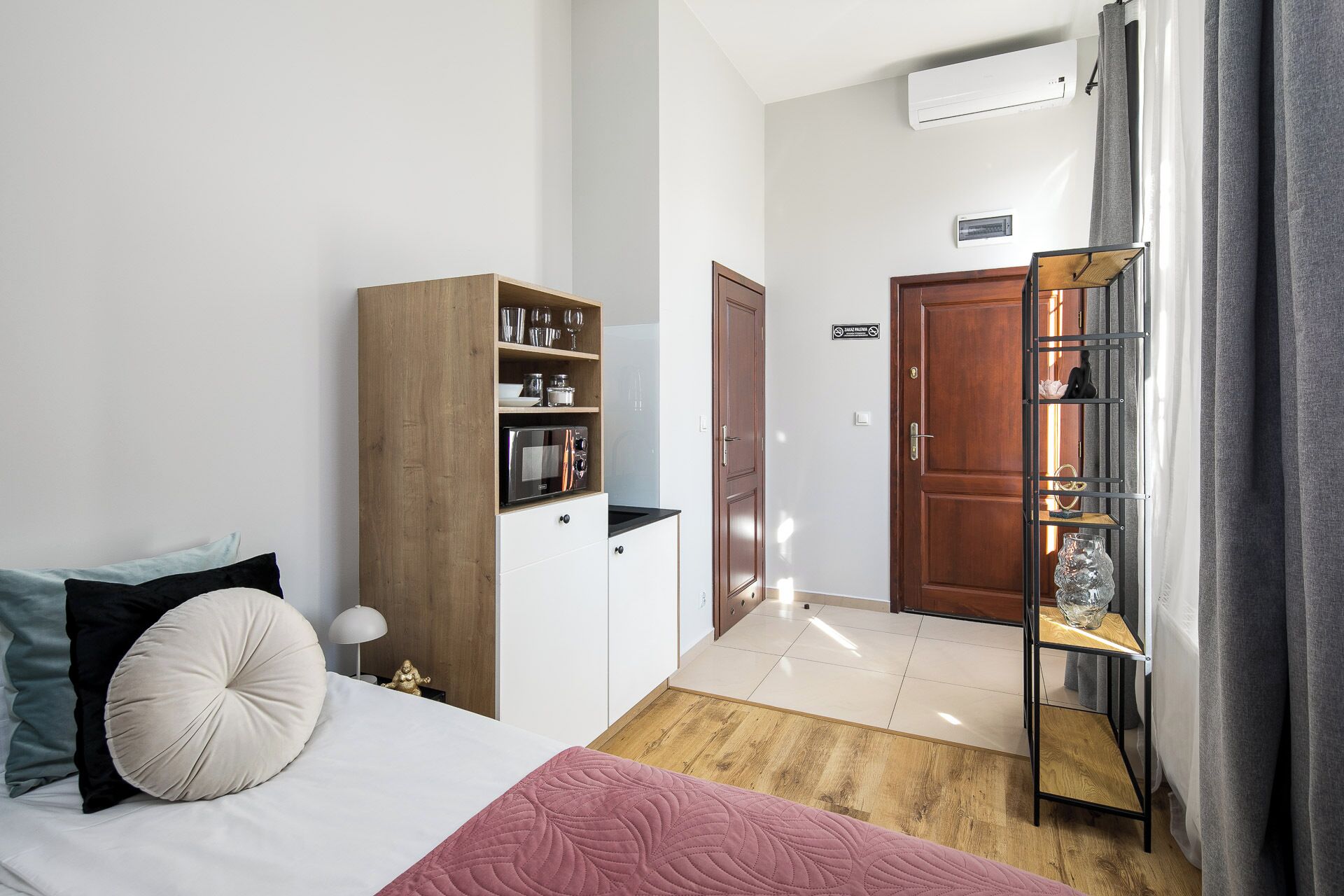A bedroom with a bed, a wardrobe, a shelf unit, and a door leading to another room.