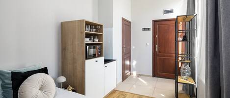 A bedroom with a bed, a wardrobe, a shelf unit, and a door leading to another room.
