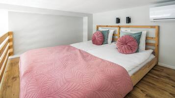 Ein Schlafzimmer mit einem hölzernen Bettgestell, weißer Bettwäsche und einer rosa Steppdecke.