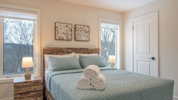 Une chambre à coucher avec un lit, deux fenêtres, une porte et des œuvres d’art accrochées au mur.