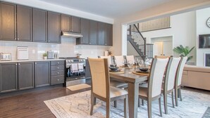 A modern kitchen with dark cabinets, a built-in oven, and a dining area with a wooden table and chairs. - Twilight Pines - Four Bedroom Cottage, Sleeps 8 (Huntsville)