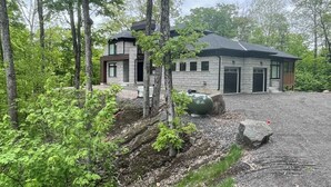 A modern two-story house with a stone facade, surrounded by dense forest. - Twilight Pines - Four Bedroom Cottage, Sleeps 8 (Huntsville)