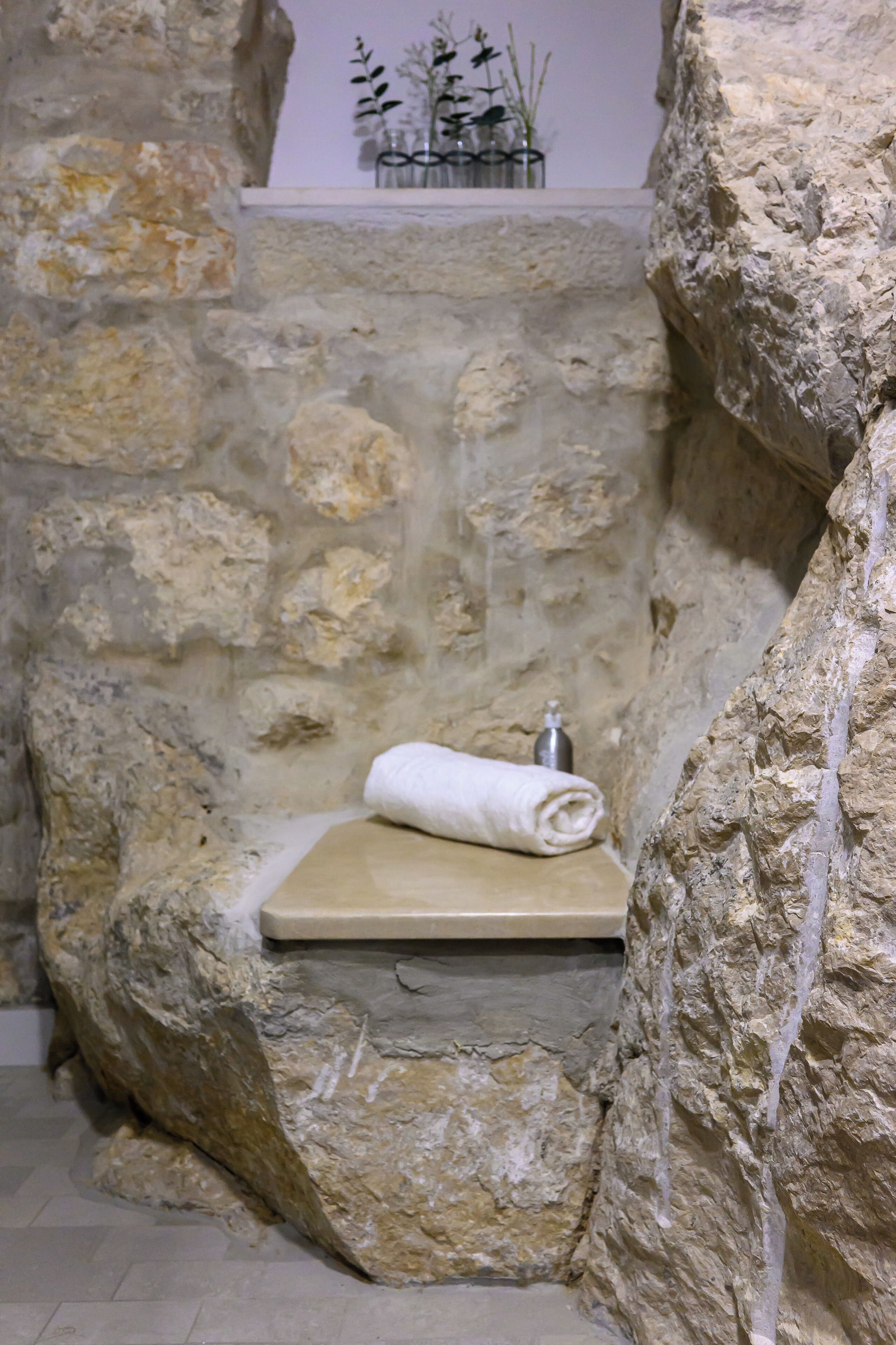 A stone-walled bathroom with a built-in bench and a towel.