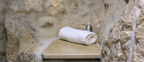 A stone-walled bathroom with a built-in bench and a towel.