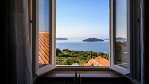 A window with a view of a coastal landscape, including a body of water and distant islands.