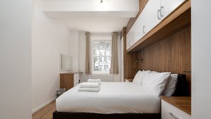 Una camera da letto moderna con un letto grande, una testiera in legno e una finestra con tende.