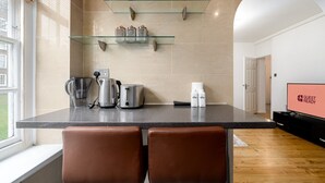 Una cucina moderna con un piano di lavoro in granito, elettrodomestici in acciaio inossidabile e ripiani in vetro.