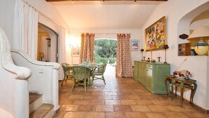 A dining area with a table and chairs, a cabinet, and a painting on the wall. - Villa with swimming pool walking distance from the beach (Ramatuelle)