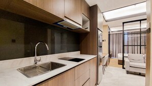A modern kitchen with a stainless steel sink, wooden cabinets, and a built-in oven. - Modern Sophisticated 1Br At The Smith Alam Sutera Apartment (Tangerang)