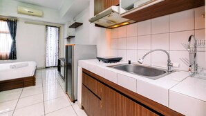 A modern kitchen with a built-in stove, sink, and wooden cabinets. - Nice And Wonderful Studio At Margonda Residence 2 Apartment (Depok)