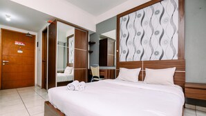 A hotel room with a large bed, wooden headboard, and a mirror above it. - Nice And Wonderful Studio At Margonda Residence 2 Apartment (Depok)
