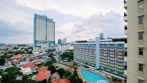 A high-rise hotel with multiple floors, a swimming pool, and a view of surrounding buildings. - Nice And Wonderful Studio At Margonda Residence 2 Apartment (Depok)