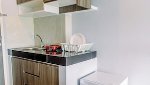 Uma cozinha moderna com bancada preta, pia de aço inoxidável e geladeira branca.