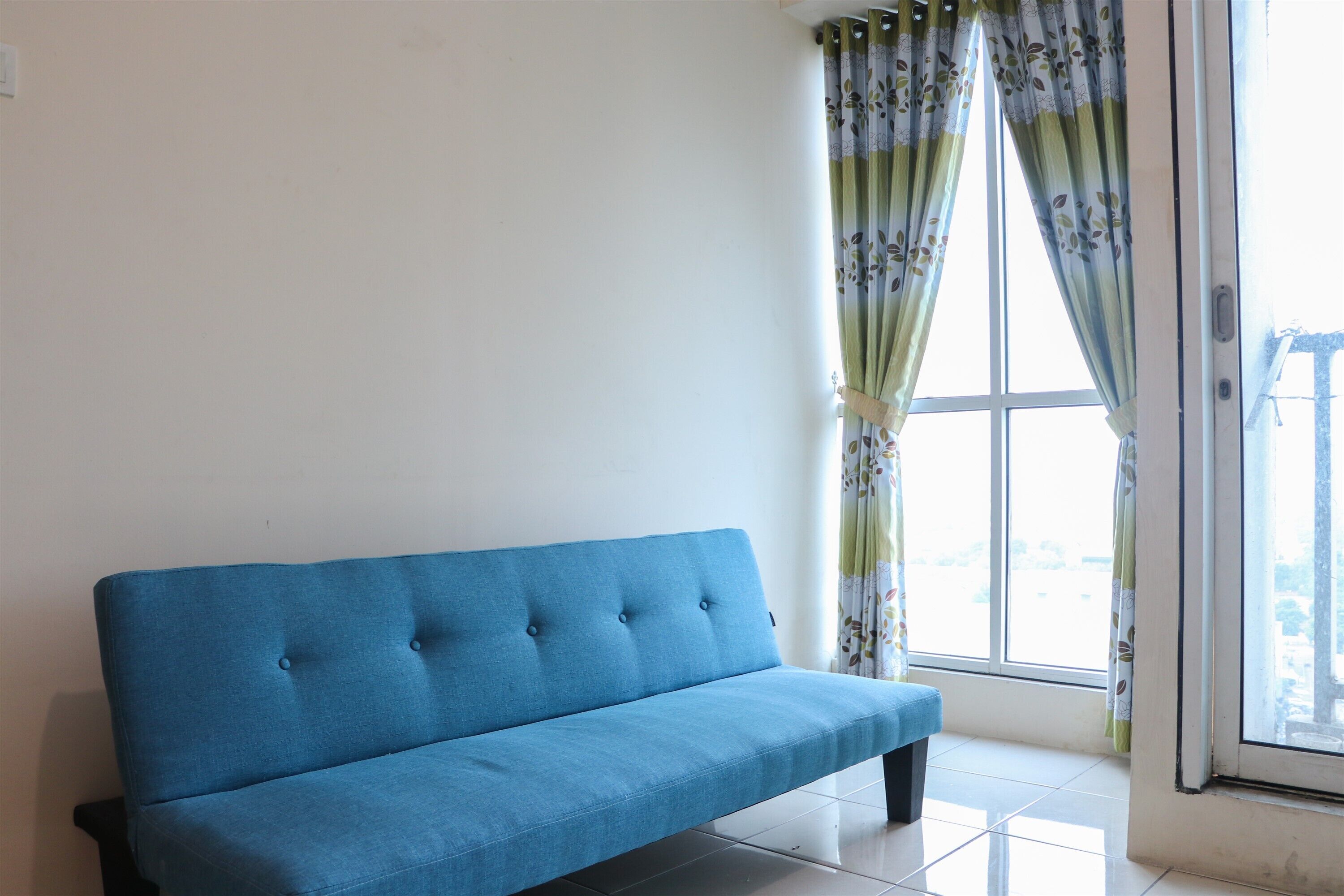 A blue sofa in a room with a large window and curtains.