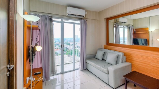 Una habitación de hotel con sofá, mesa, lámpara, televisor y aire acondicionado.