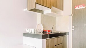 A modern kitchen with white cabinetry, a black countertop, and a stainless steel sink. - Fancy And Nice Studio At Serpong Garden Apartment (Cisauk)