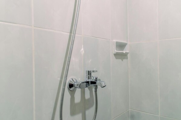 A shower area with a chrome faucet and a handheld showerhead. - Fancy And Nice Studio At Serpong Garden Apartment (Cisauk)