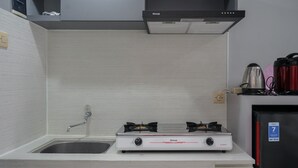 A kitchen with a white countertop, a sink, a gas stove, and a refrigerator. - Brand New And Super Cozy Studio Room At Sky View Apartment (South Tangerang)