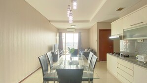 A modern kitchen with a dining area, featuring a glass table and chairs, a built-in oven, and a large window with curtains. - Spacious And Good 3Br At Thamrin Residence Apartment (Jakarta)
