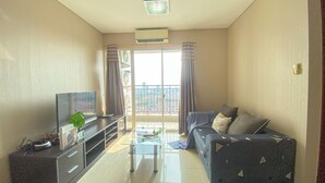 A modern living room with a flat-screen TV, a glass coffee table, and a sofa with patterned cushions. - Spacious And Good 3Br At Thamrin Residence Apartment (Jakarta)