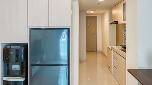 A modern kitchen with a stainless steel refrigerator, a water dispenser, and wooden cabinets. - Restful And Chic 2Br At Meikarta Apartment (Cikarang)