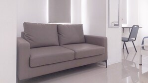 Una habitación moderna y minimalista con un sofá gris, un escritorio y una silla.