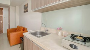 Une cuisine moderne avec un évier, une cuisinière et un petit canapé orange.