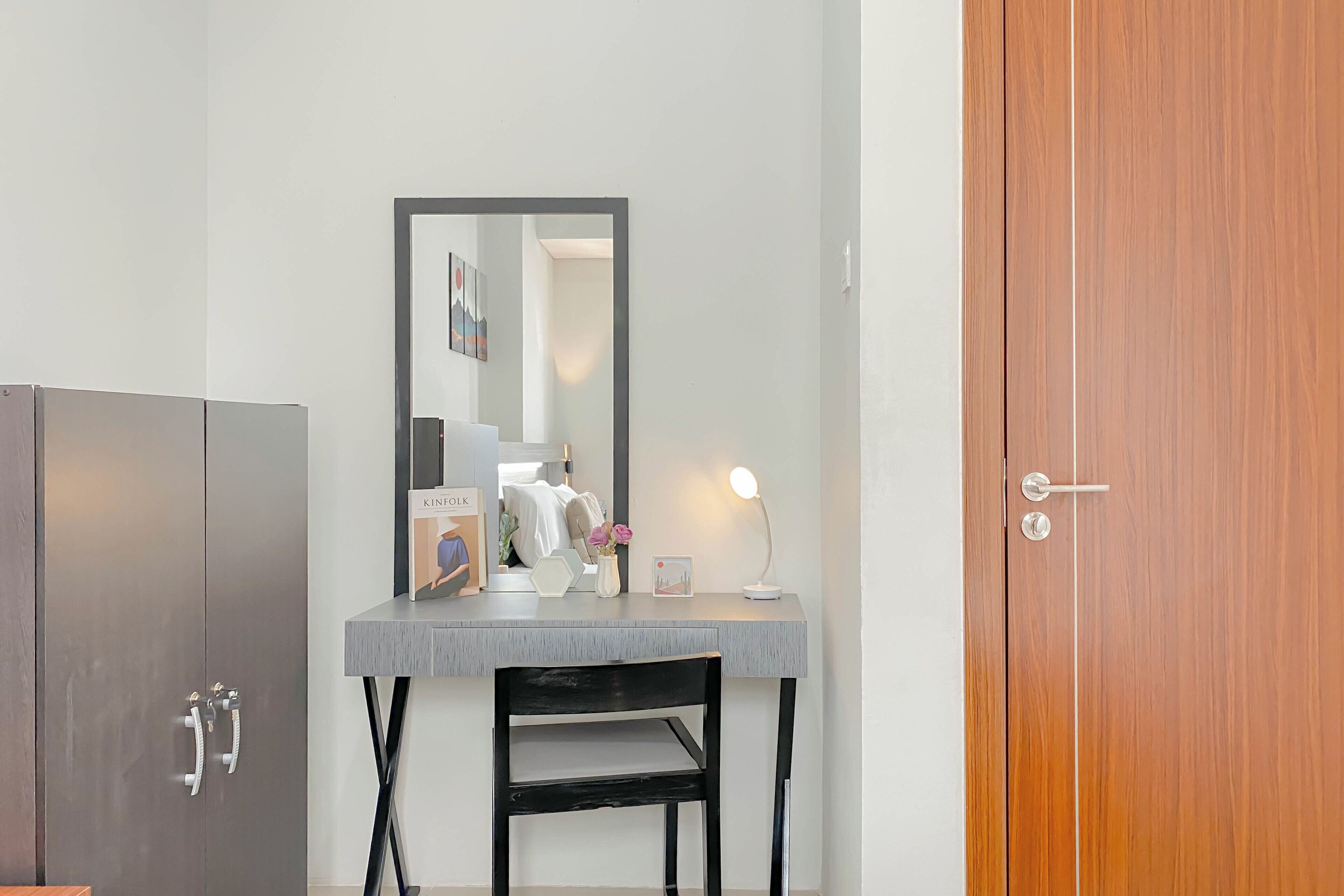 Une pièce avec un bureau gris, une chaise noire, une armoire en bois et une porte en bois.