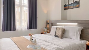 Une chambre d’hôtel avec un lit soigneusement fait, une table de chevet avec une lampe et une œuvre d’art accrochée au mur.