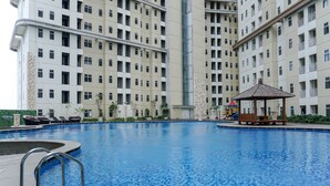 A swimming pool with a gazebo and lounge chairs, surrounded by high-rise residential buildings. - Warm And Comfortable 1Br Apartment At Vittoria Residence (Jakarta)