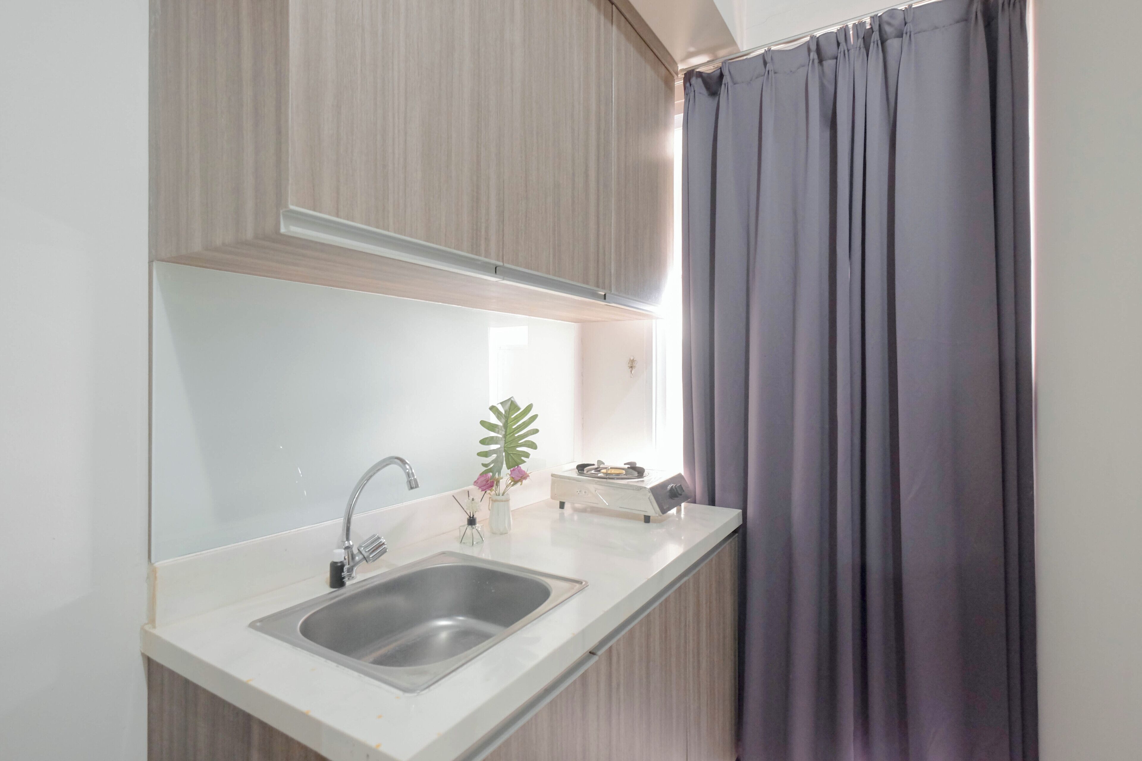 A modern kitchen with a built-in sink, wooden cabinets, and a window with curtains.