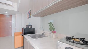 A modern kitchen with a stainless steel sink, a gas stove, and a small countertop area. - Warm And Comfy 2Br Apartment At Vittoria Residence (Cikarang)