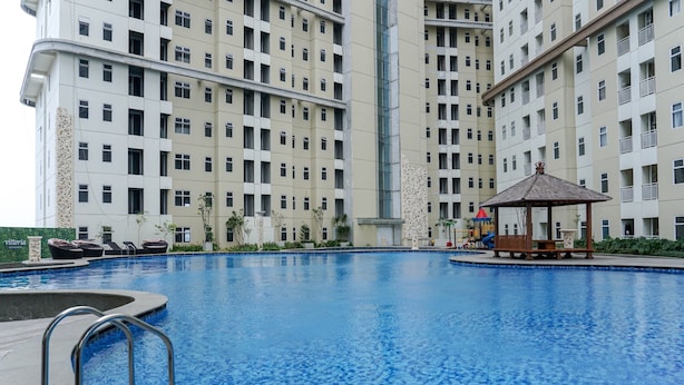 A swimming pool with a gazebo and lounge chairs, surrounded by high-rise residential buildings. - Warm And Comfy 2Br Apartment At Vittoria Residence (Cikarang)