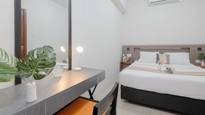 A hotel room with a bed, bedside table, mirror, and a potted plant. - Warm And Comfy 2Br Apartment At Vittoria Residence (Cikarang)