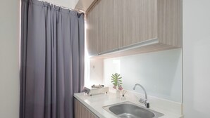 A modern kitchen with a sink, a stove, and a plant on the counter.