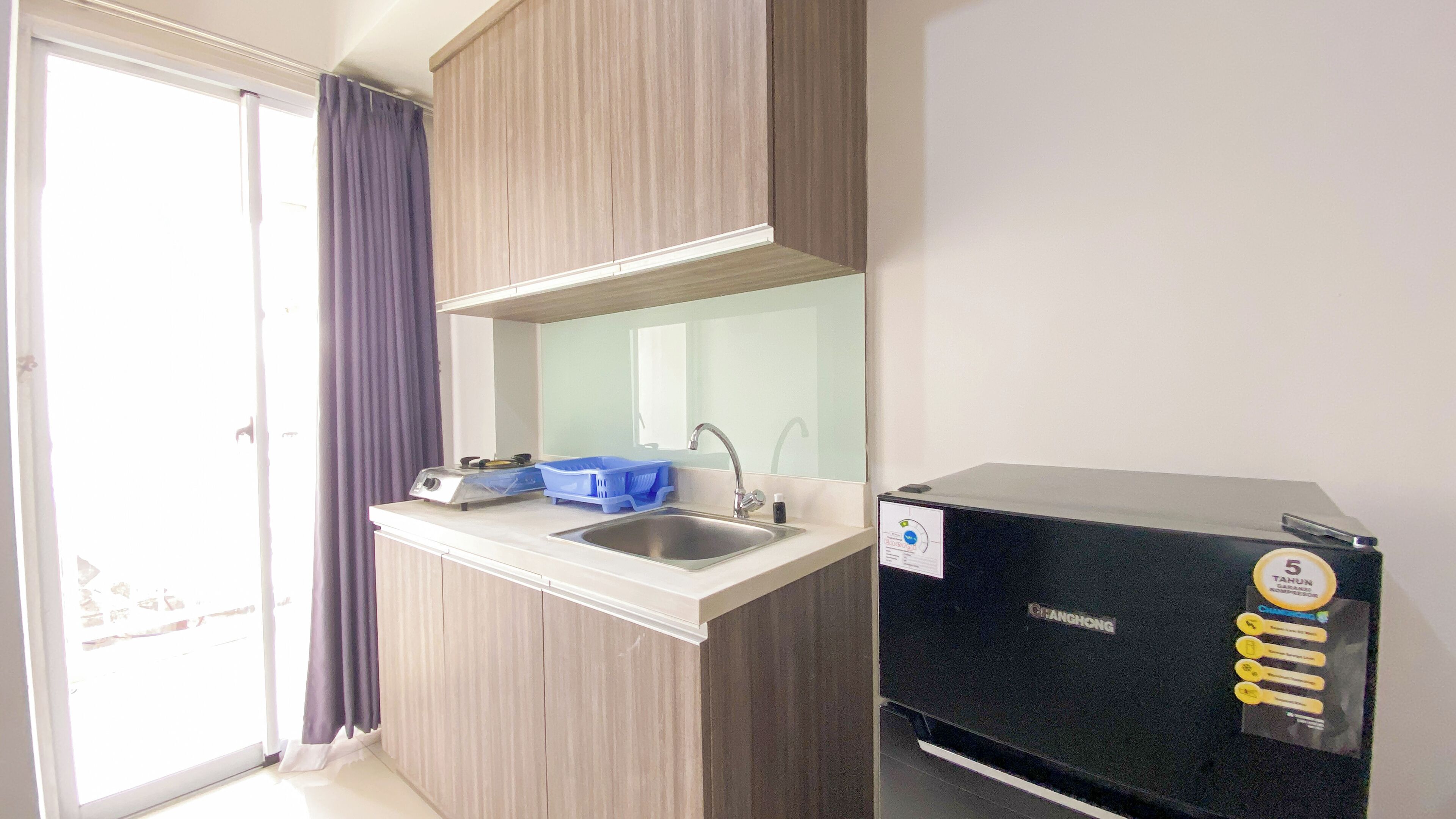A compact kitchenette with a sink, a stove, and a compact refrigerator.