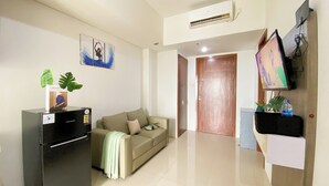 Un salon moderne avec un canapé, un meuble de rangement noir pour appareils électroniques, un téléviseur à écran plat et une porte donnant sur une autre pièce.