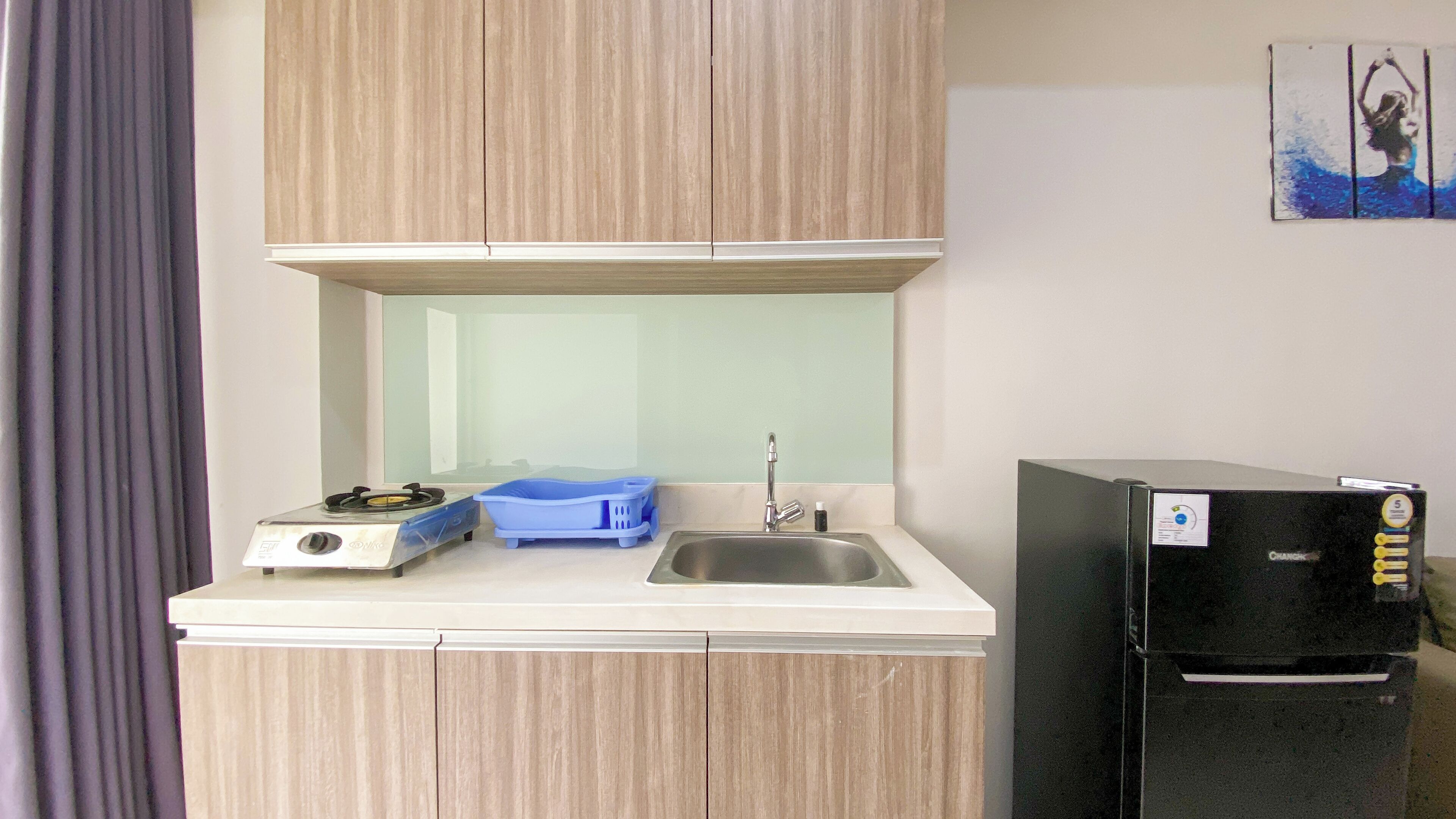 A compact kitchenette with a gas stove, sink, and a black refrigerator.