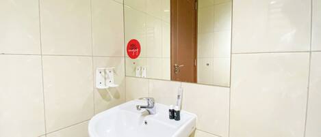 Ein Badezimmer mit einem weißen Waschbecken, einem Spiegel und einer Holztür.